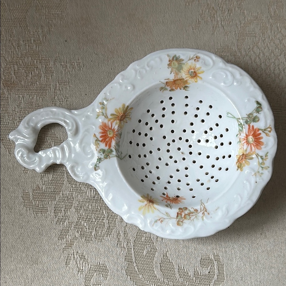 Floral porcelain tea strainer, circa 1920s, with orange and yellow flowers